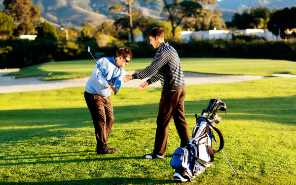 Huấn luyện viên chỉnh tư thế cầm gậy cho golfer